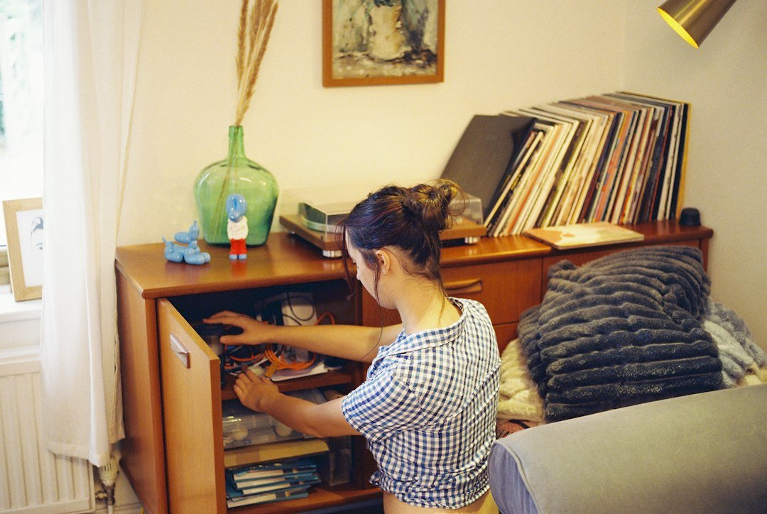 Person organising cables and equipment in a cabinet while decluttering a home office before a move
